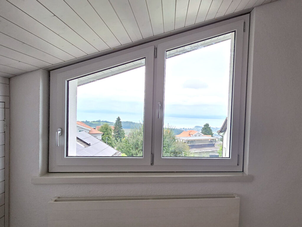 Abgeschrägte weiss Kunststofffenster im Dachgeschoss, die speziell für diese Architektur angefertigt wurden. Fensterreparatur und Fenstereinstellung in der Ostschweiz bei klemmenden Fenstern und Zugluftproblemen